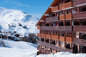 Ett hotell med flera våningar och balkonger, beläget med en snötäckt bergskedja som bakgrund.
