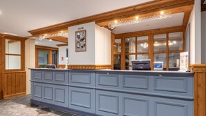 A reception desk with a blue panel, wooden accents, and a framed picture on the wall.