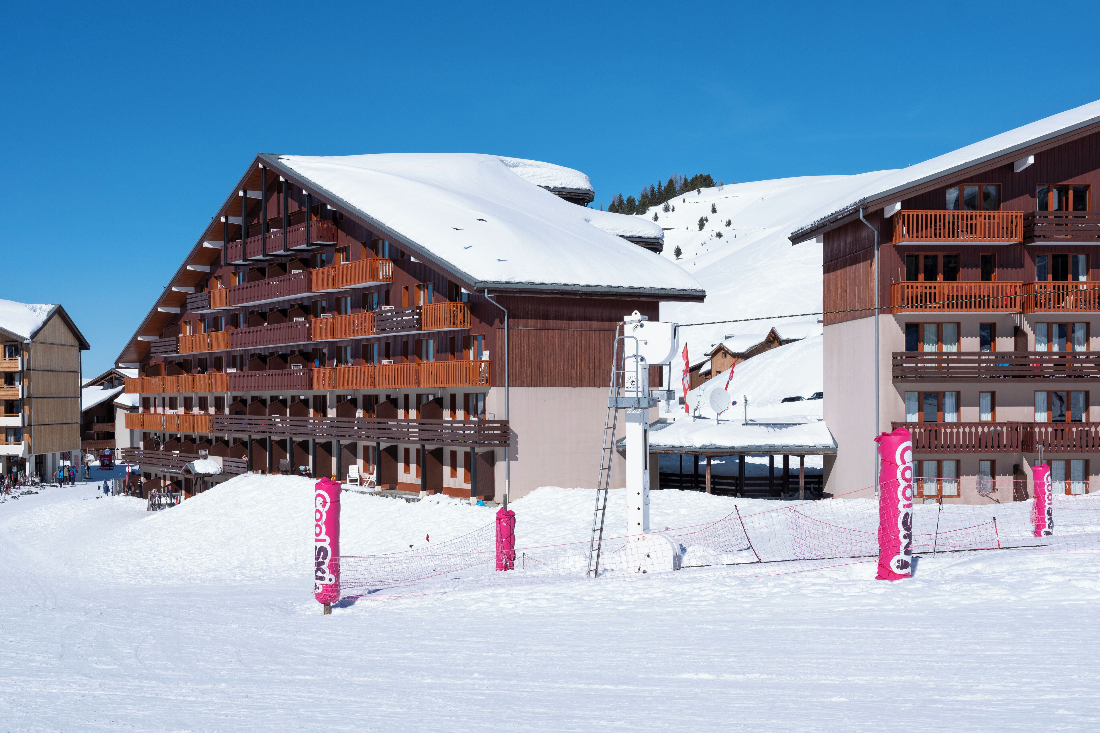 A ski resort with multi-story wooden buildings, ski lifts, and snow-covered slopes.