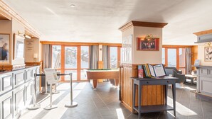 A spacious indoor area with a pool table, a billiards table, and a reception desk.