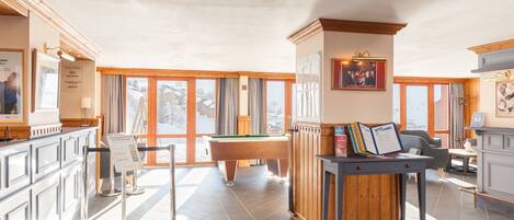 Un grand espace intérieur comprenant une table de billard, une table de snooker et un comptoir d’accueil.