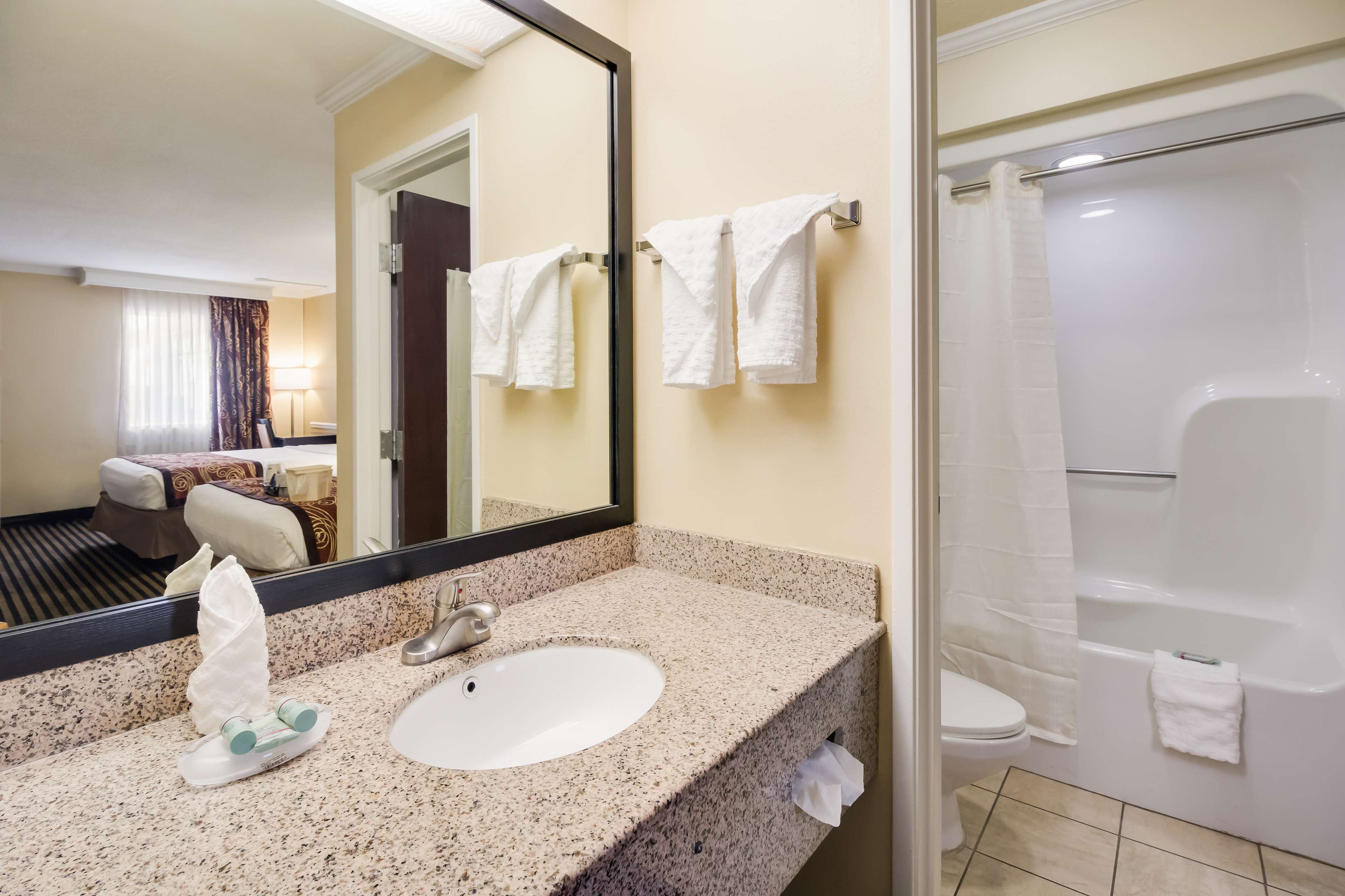 A hotel bathroom with a sink, mirror, and a shower area.