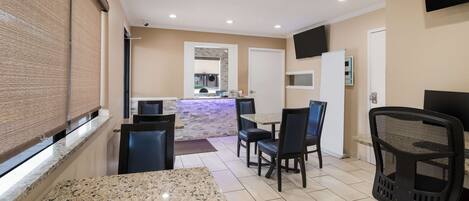 A hotel room with a dining area, a kitchen, and a TV mounted on the wall.