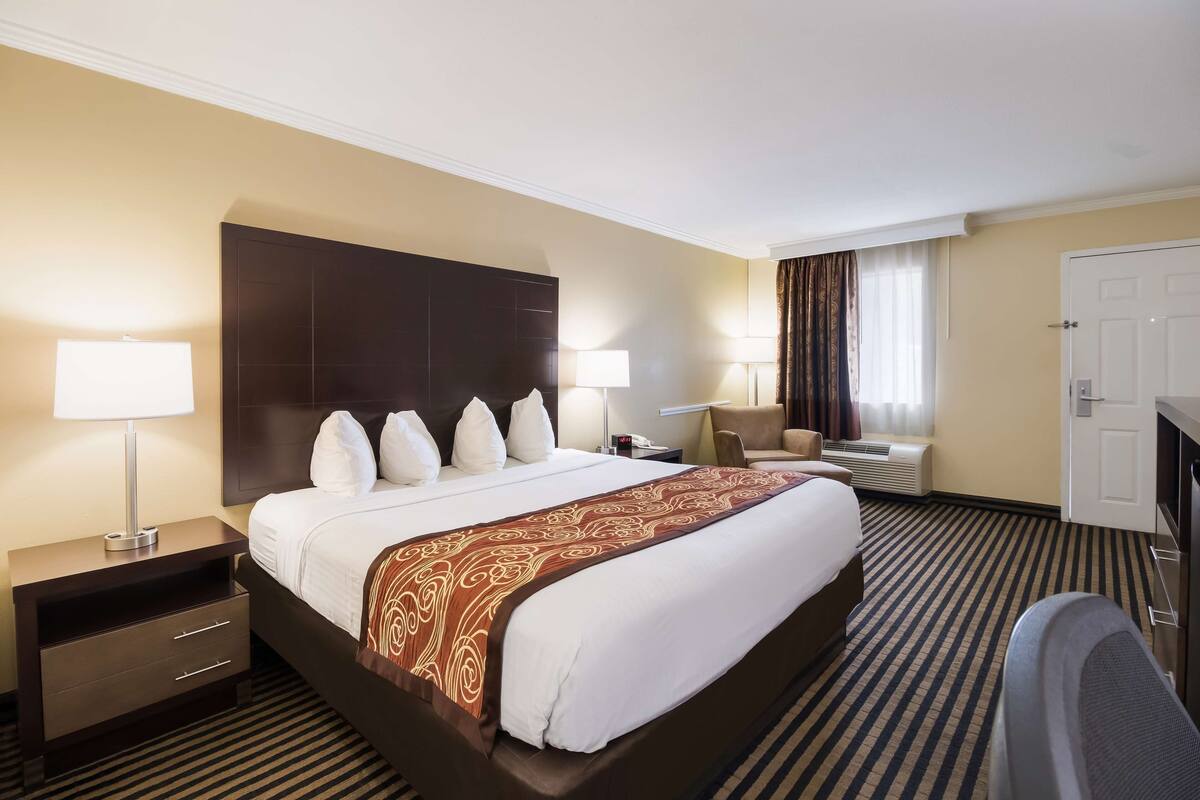 A hotel room with a large bed, a nightstand, a desk, a chair, and a television.
