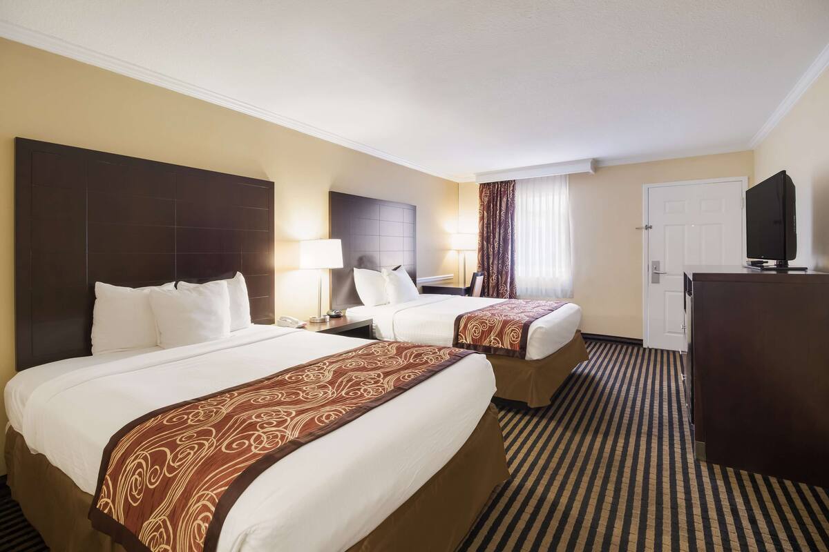 A hotel room with two beds, a TV, a desk, and a wardrobe.