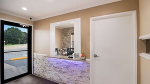 A reception area with a stone wall, a counter, and a door. - Best Western McKenzie (McKenzie)