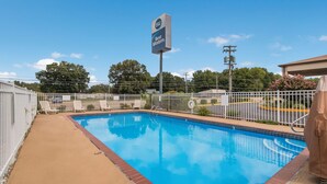 A swimming pool with a white fence, a Best Western sign, and a clear blue sky. - Best Western McKenzie (McKenzie)