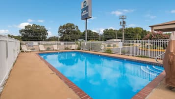 Una piscina al aire libre, sillones reclinables de piscina