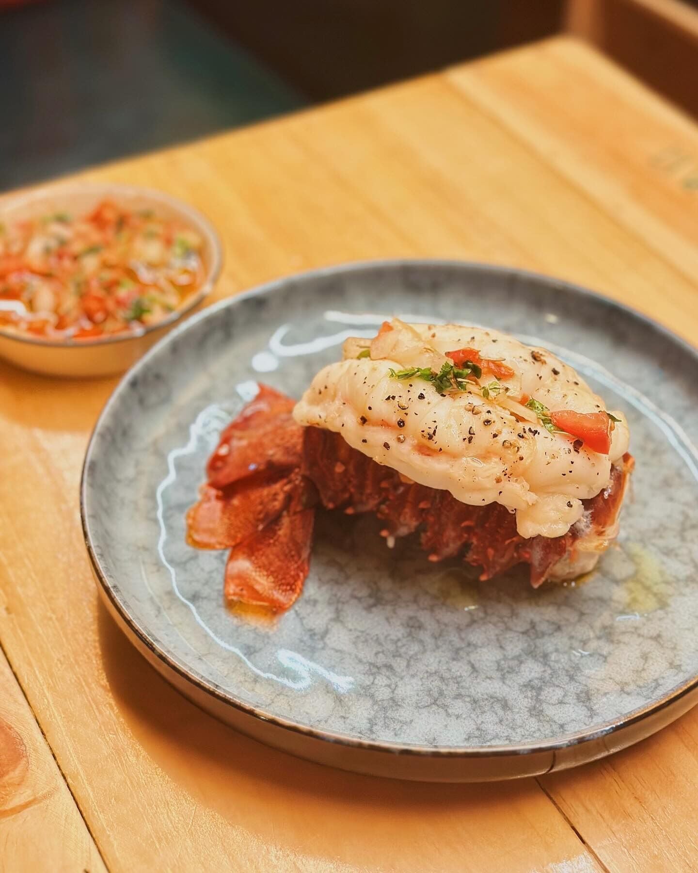 A plate with a fish dish and a side salad on a wooden table.