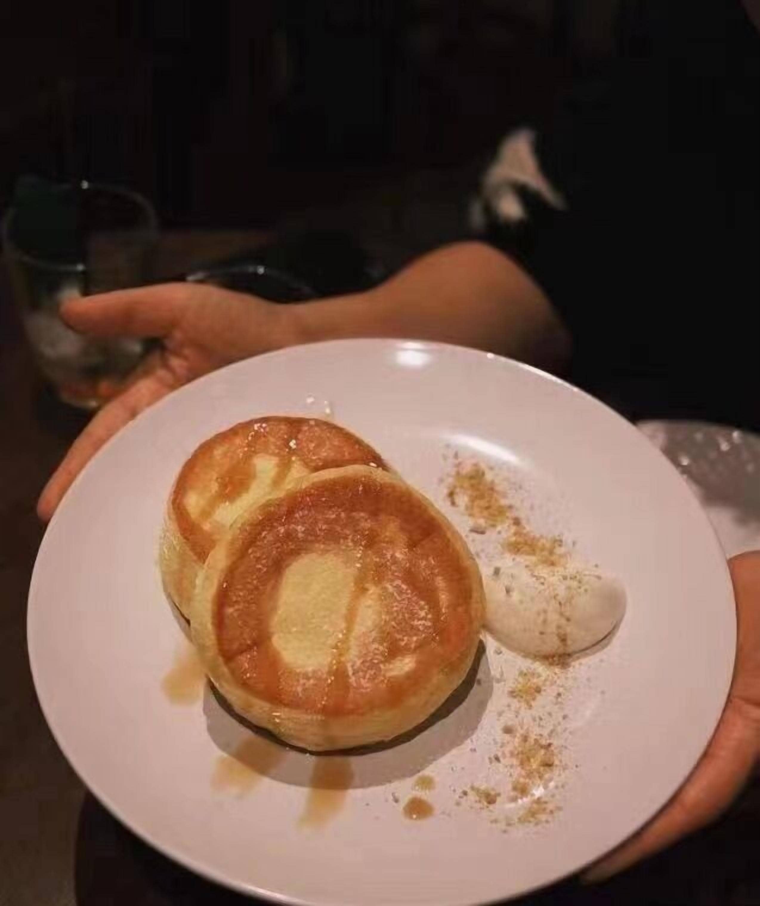 Un plato con dos tortitas y un poco de almíbar.