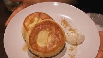 Un plato con dos tortitas y un poco de almíbar.