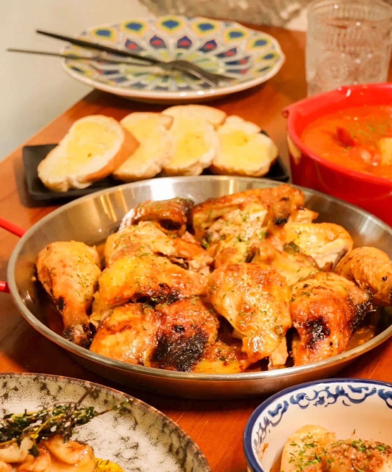 Una mesa con un recipiente de pollo cocido, un tazón de sopa y platos con comida.