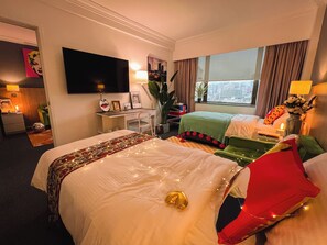 Relax in comfort with a large bed, a second bed, a desk, and a flat-screen TV, all set against a city view.