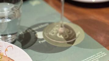 A cocktail glass with a frothy top, placed on a table with a menu underneath.
