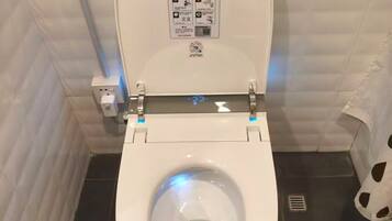 Un inodoro con la tapa levantada, un cartel con indicaciones y un código QR.