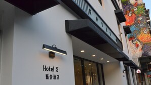 Hotel S with a modern facade, a glass entrance, and a colorful mural on the adjacent building. - Macau Hotel S (Macau)