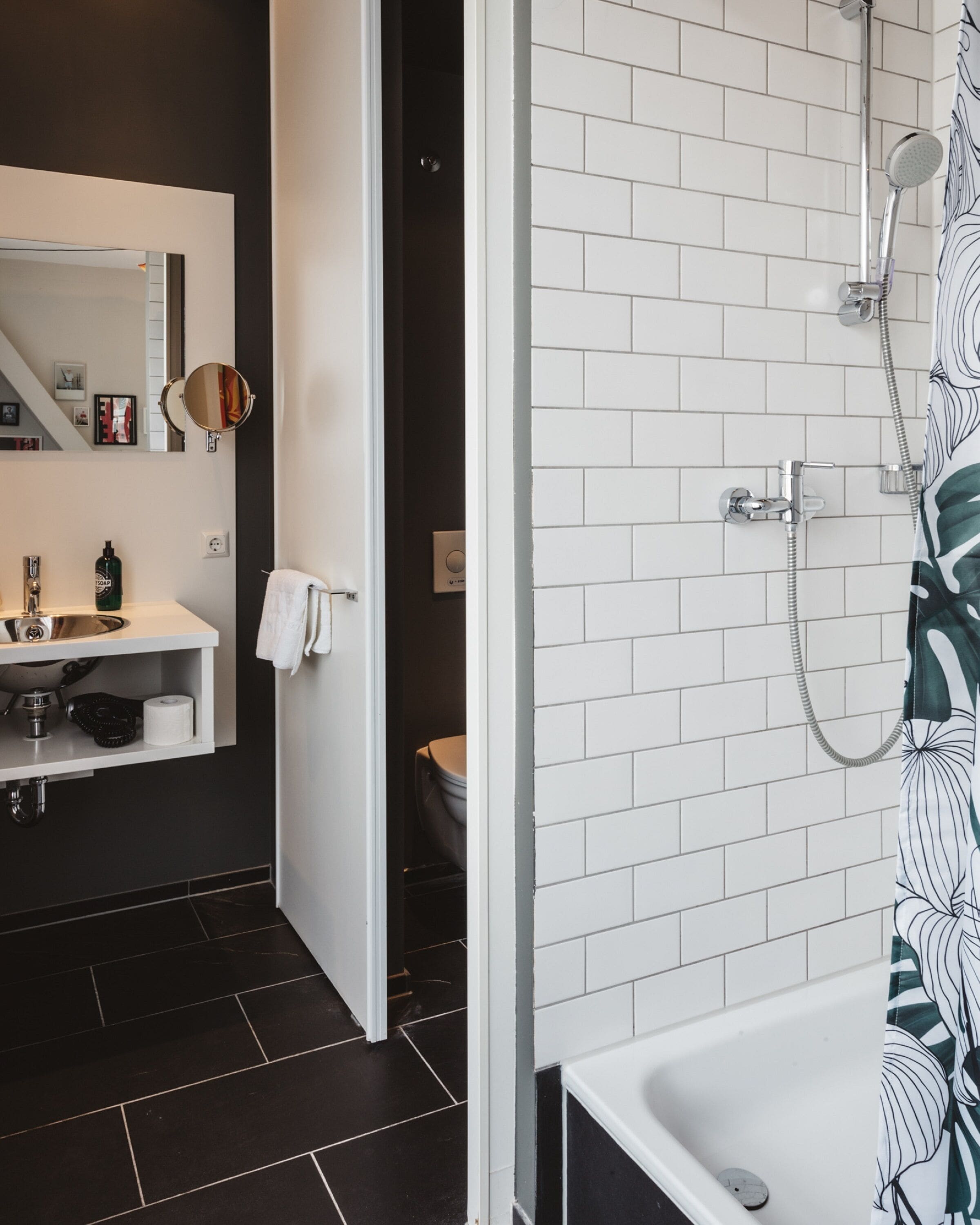 Un baño moderno con lavamanos, espejo y ducha blancos.