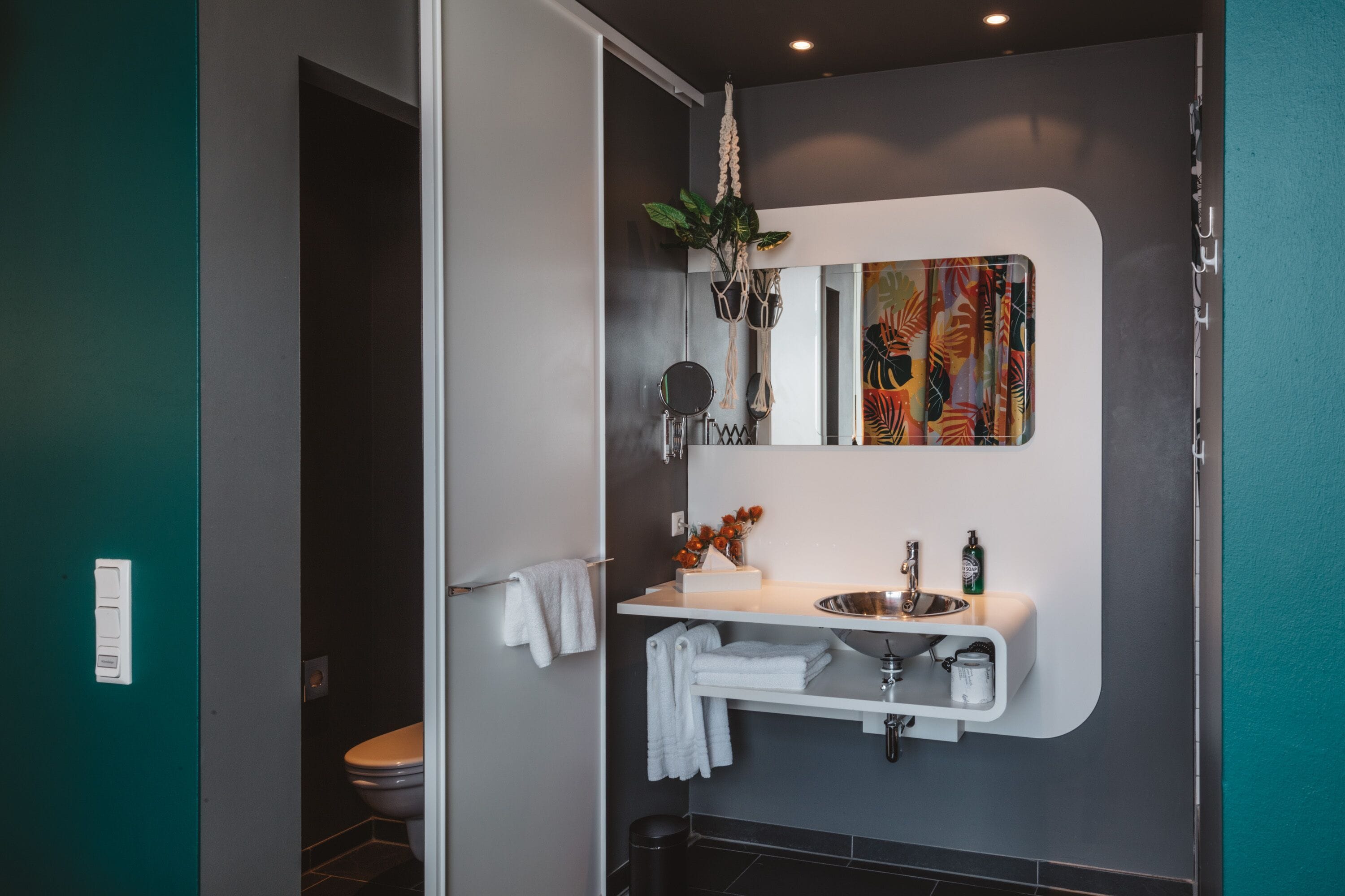 A modern bathroom with a white vanity, a mirror, and a decorative plant.