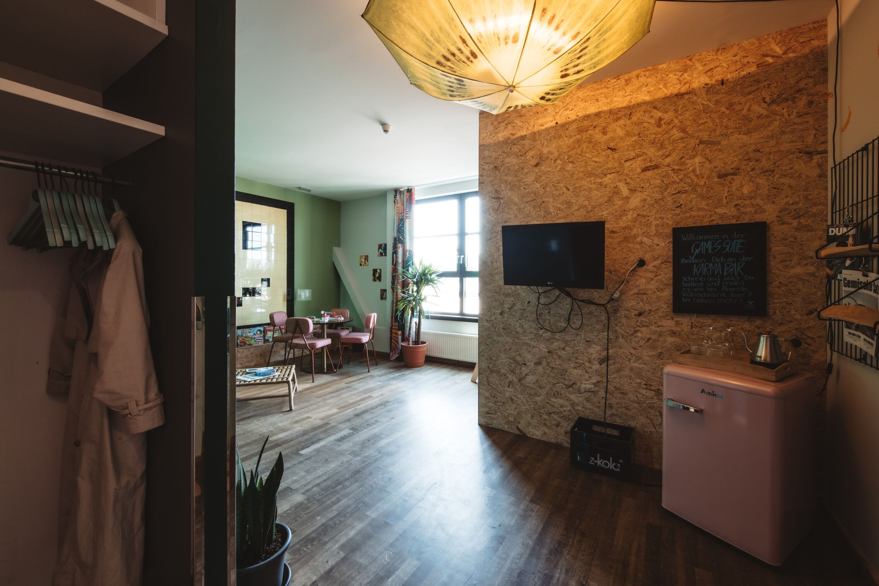 A modern living room with a stone wall, a flat-screen TV, and a small kitchenette.