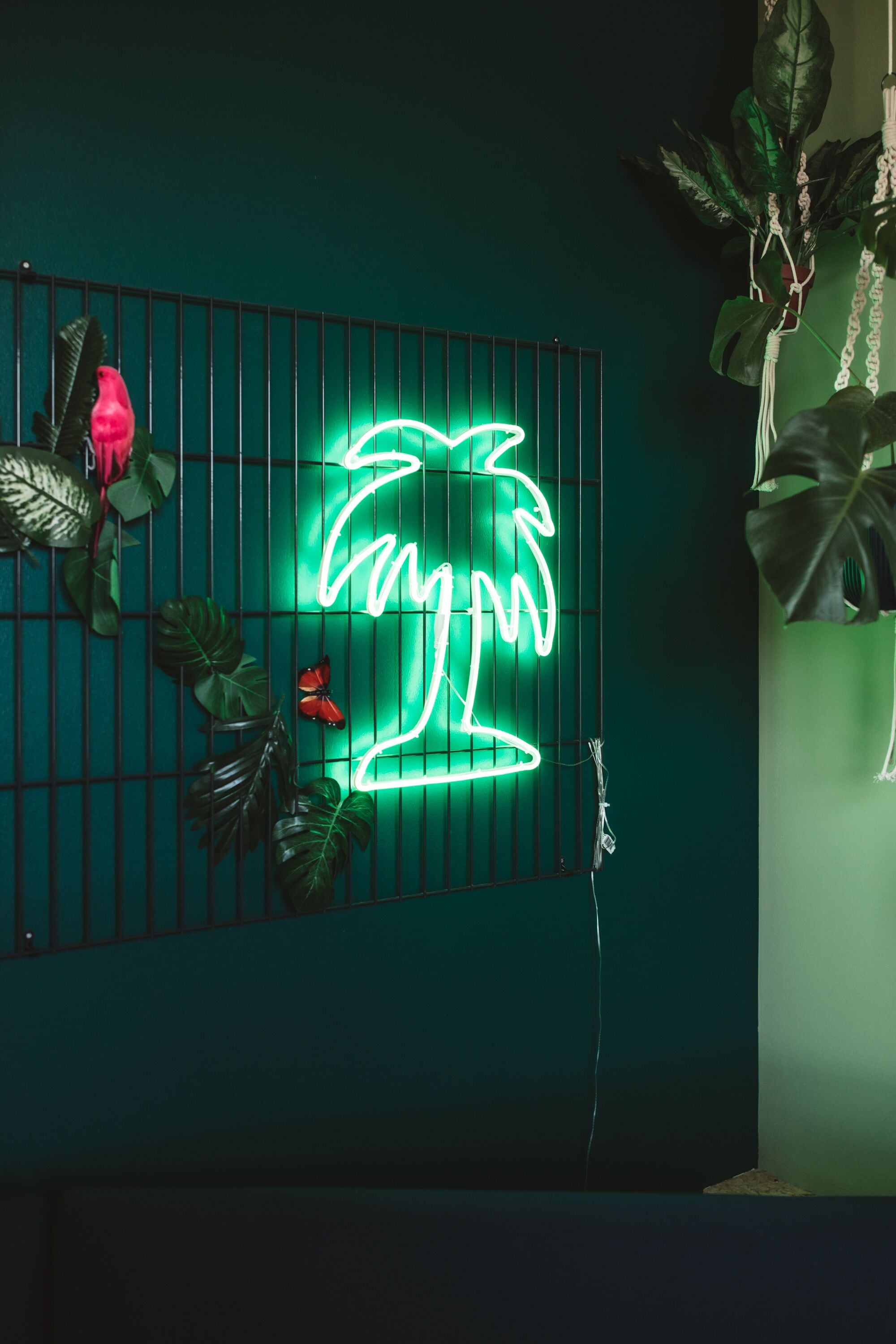 Un letrero de palmera neón sobre una pared verde oscuro.