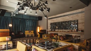 A cozy lounge area with wooden furniture, a fireplace, and a wall of framed photos. - Superbude Altona Paradise (Hamburg)