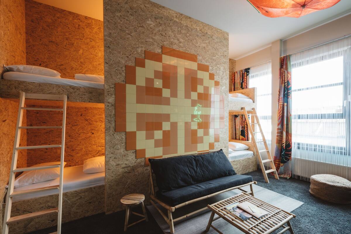 A room with bunk beds, a sofa, a coffee table, and a large wall art piece.