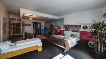 Een hotelkamer met twee bedden, een rode hoofdbord, een grote spiegel en een plant.