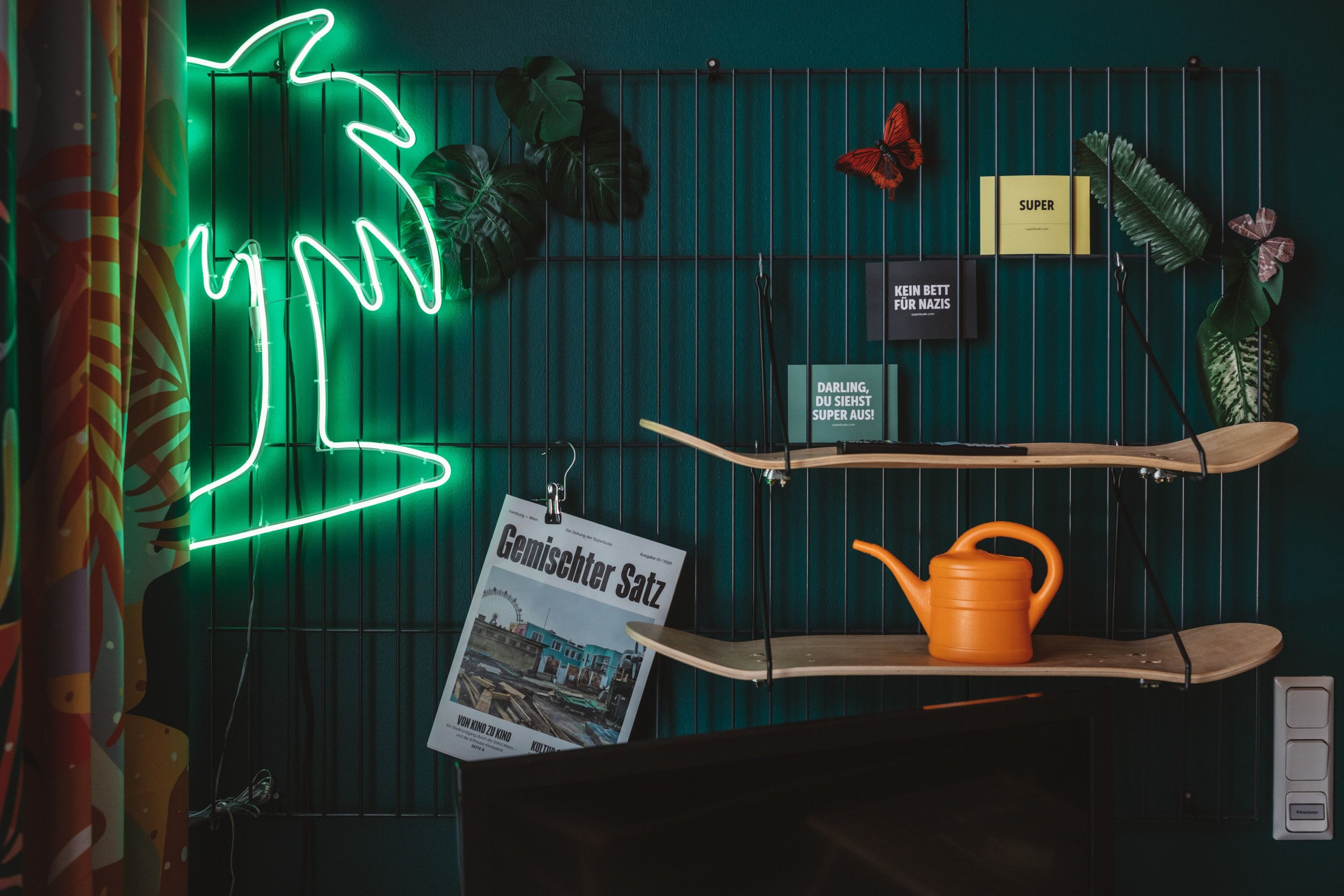 A room with a neon tree, a poster, a shelf with a kettle, and a sign with text.