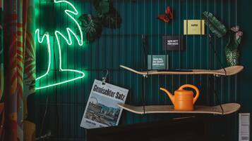 A room with a neon tree, a poster, a shelf with a kettle, and a sign with text.