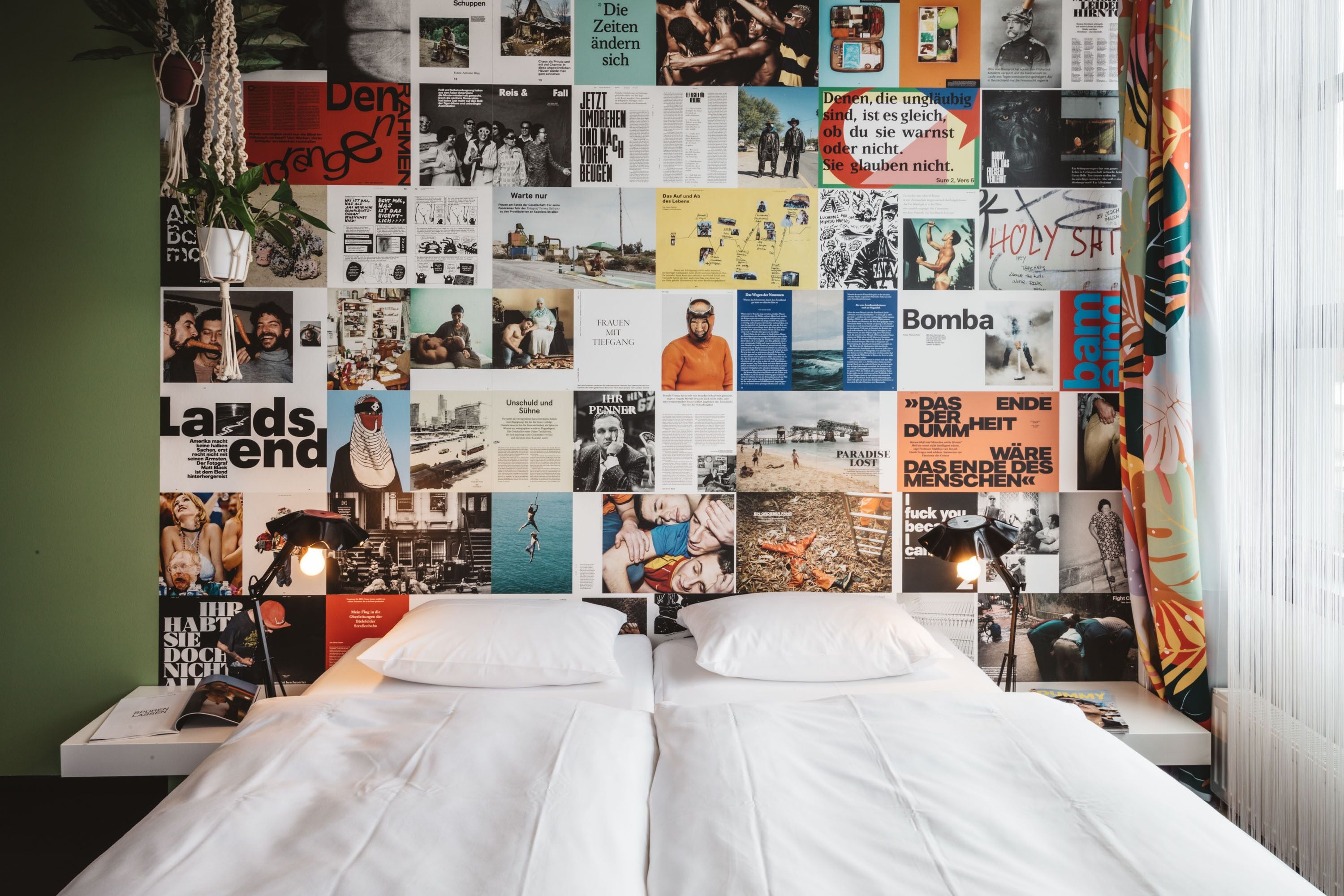 Ein Schlafzimmer mit einem Bett, einer Nachttischlampe und einer Wand, die mit verschiedenen Postern und Fotos bedeckt ist.