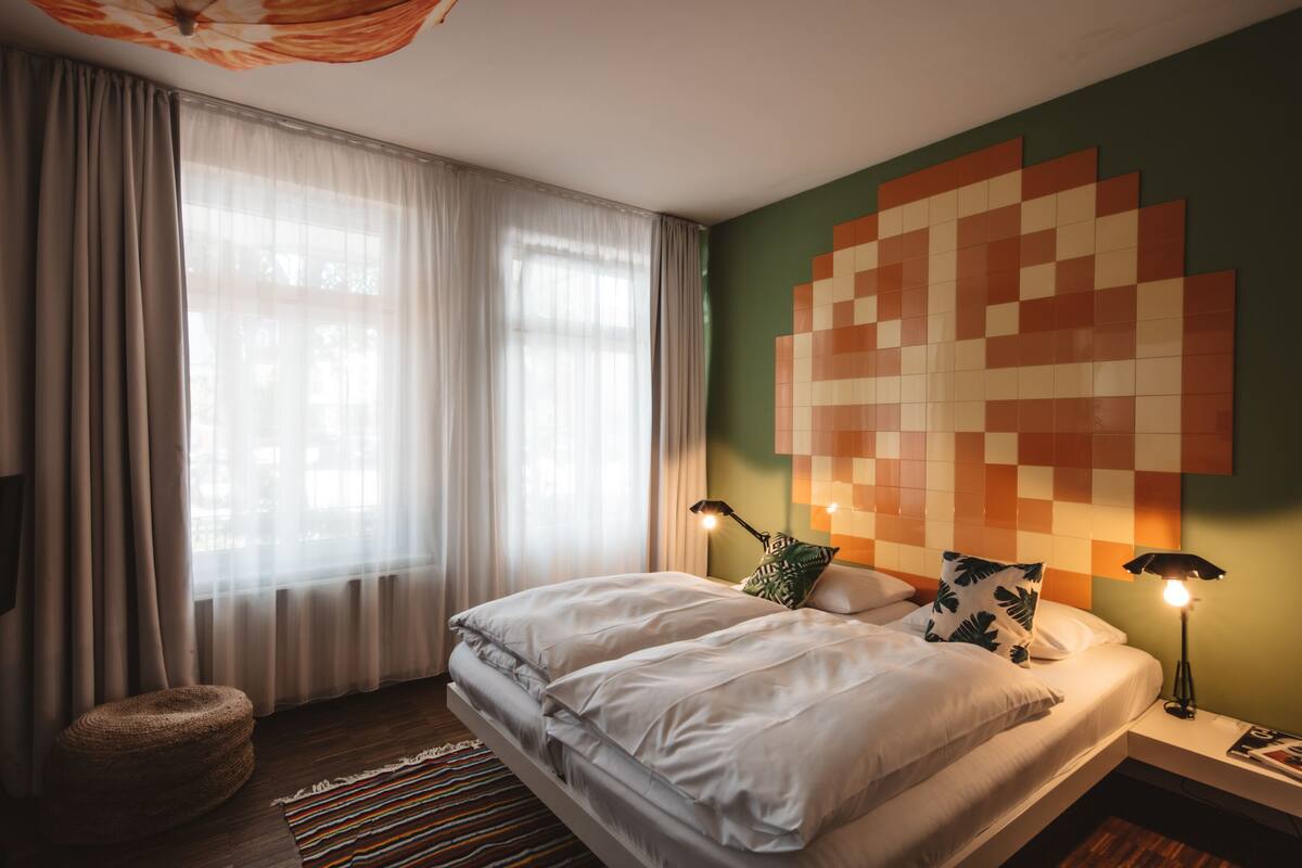 A modern bedroom with a large bed, a wall art piece, and a nightstand with a lamp.