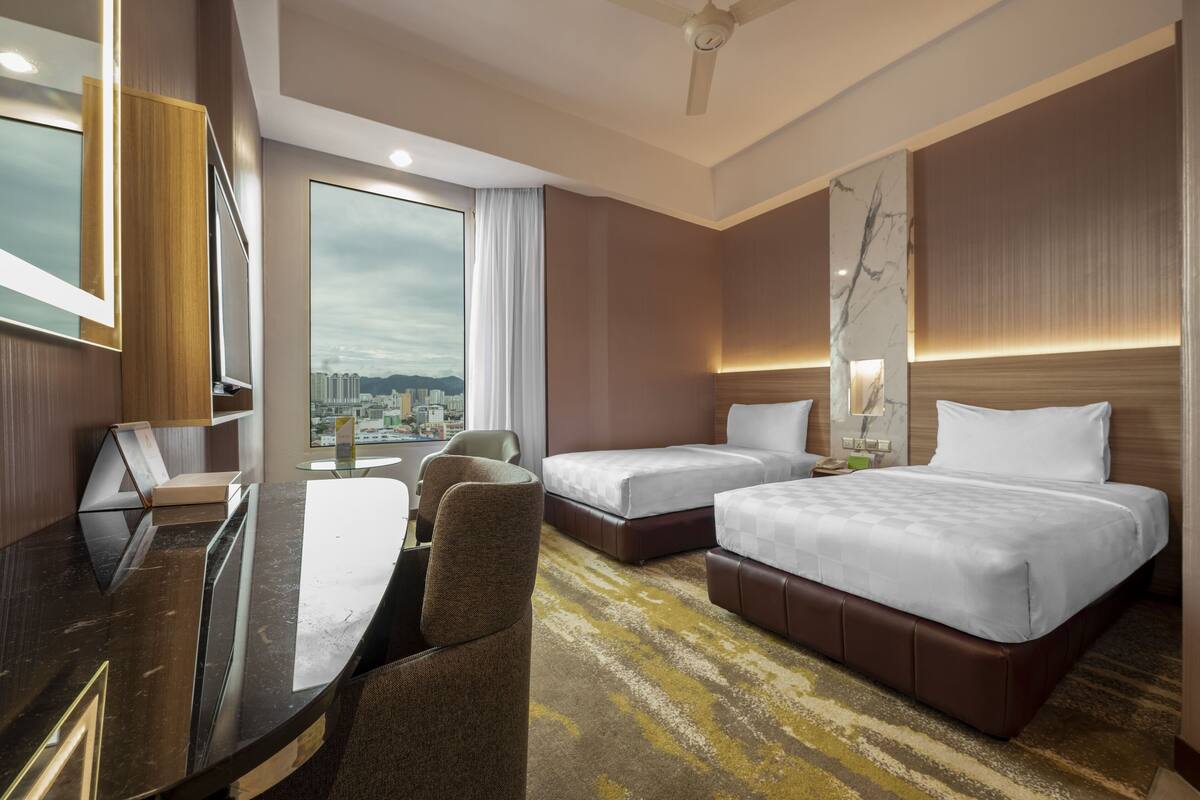 A hotel room with a desk, two beds, a large window with a city view, and a modern design.