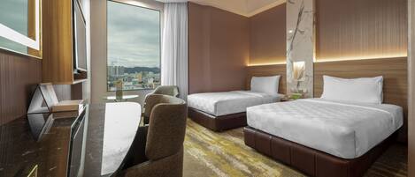 Camera d'hotel con una scrivania, due letti, un'ampia finestra vista città e un design moderno.