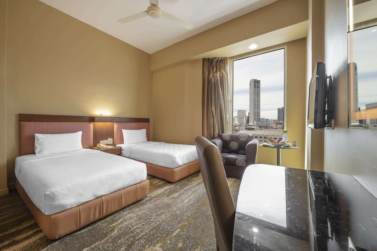 A hotel room with two beds, a desk, a chair, a television, and a large window with a city view.