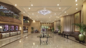 Un amplio vestíbulo con mostrador de recepción, zona de estar y una mesa de cristal decorativa.