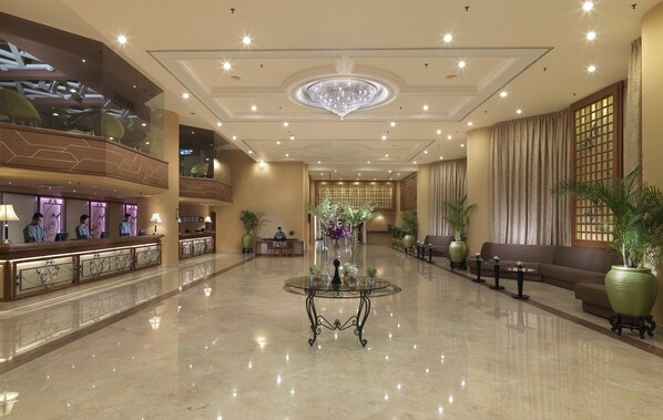 Un amplio vestíbulo con mostrador de recepción, zona de estar y una mesa de cristal decorativa.