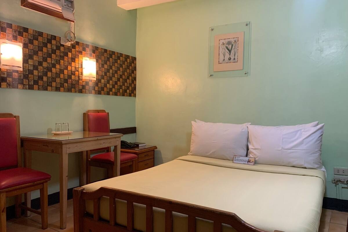 A room with a bed, a desk, and two chairs.