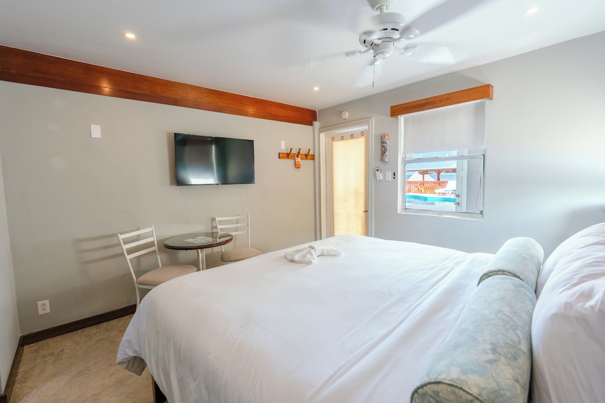 Habitación de hotel con cama, escritorio, silla, televisor y ventana con vistas.