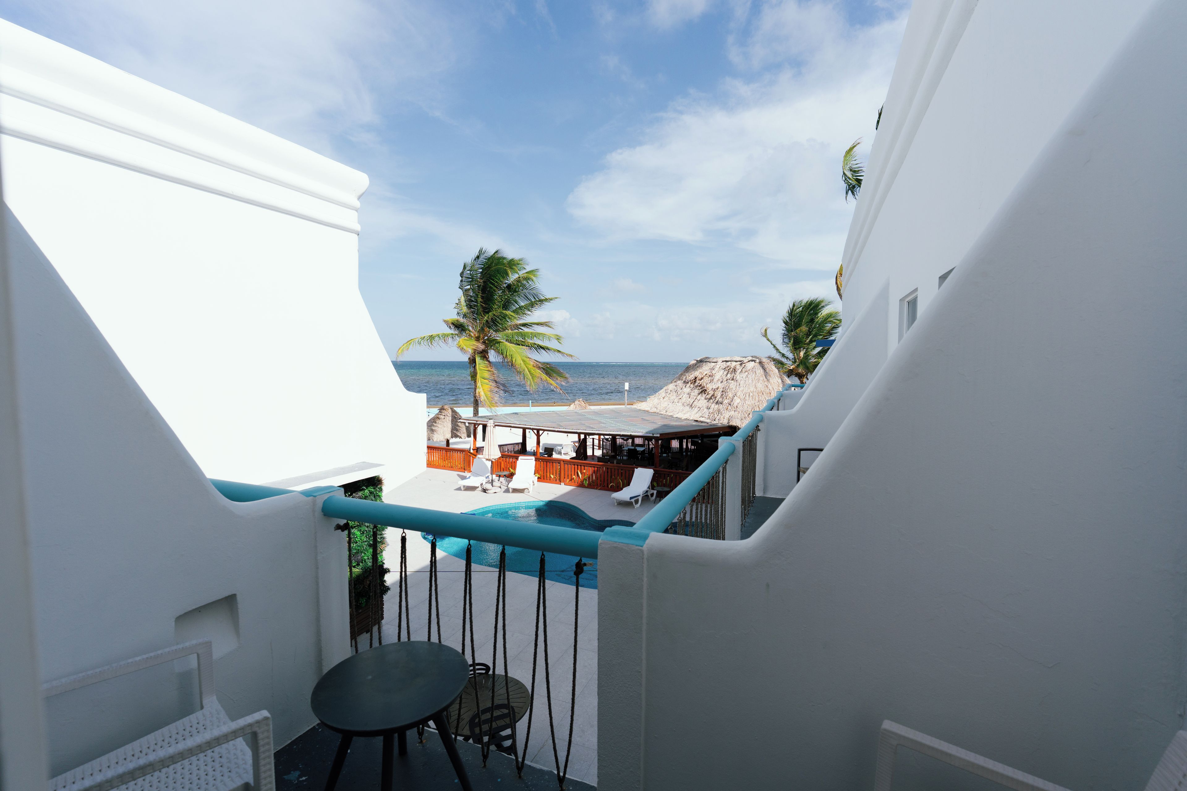 Un balcon avec une piscine, des murs blancs et une vue sur l’océan.