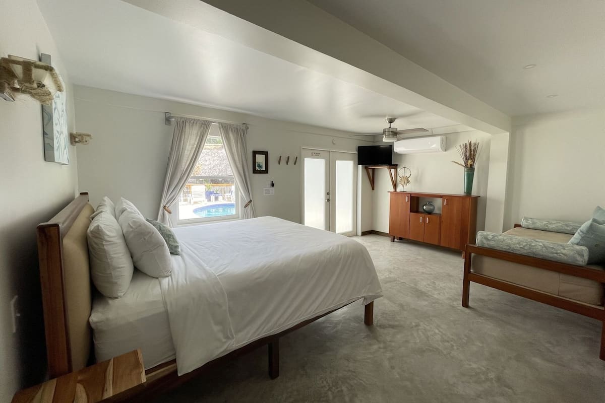 Un dormitorio con cama, cómoda de madera, televisor y vistas a una piscina.