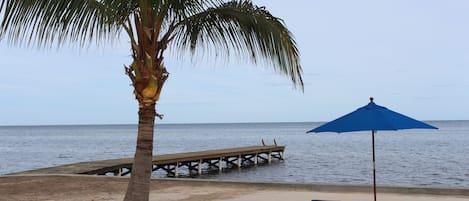 Na praia, areia branca, espreguiçadeiras, guarda-sóis