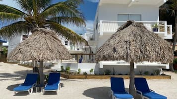 På stranden, hvidt sand, liggestole, parasoller