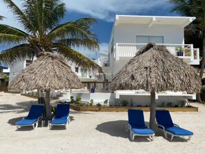 Am Strand, weißer Sandstrand, Liegestühle, Sonnenschirme