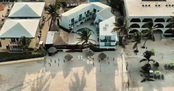 A modern building with a curved facade, multiple windows, and palm trees.