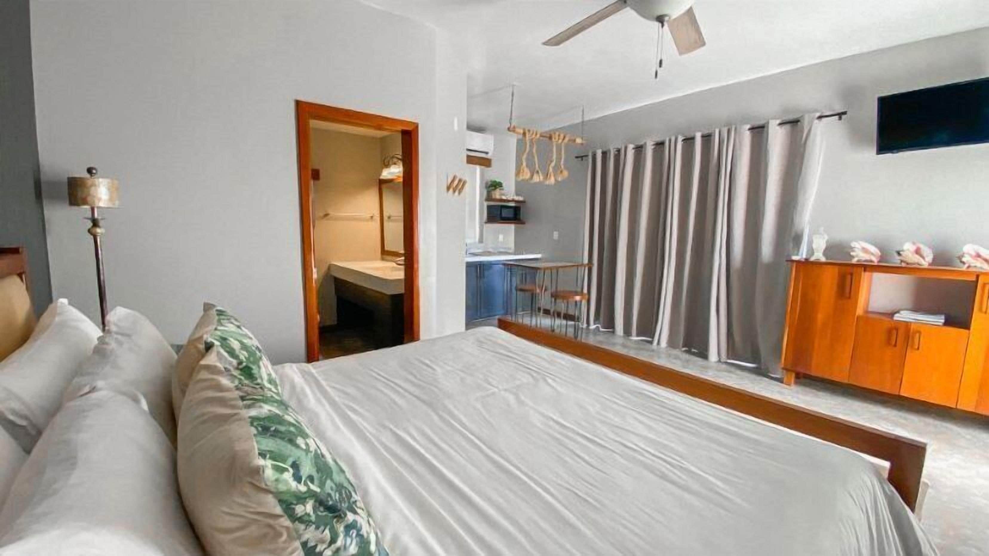 Un dormitorio con cama, escritorio, silla, armario y ventilador de techo.
