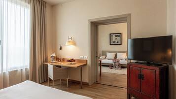 Una habitación de hotel con una cama, un escritorio con lámpara, un televisor y un armario.