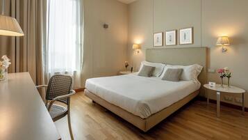 A hotel room with a large bed, two bedside tables, a desk, and a chair.