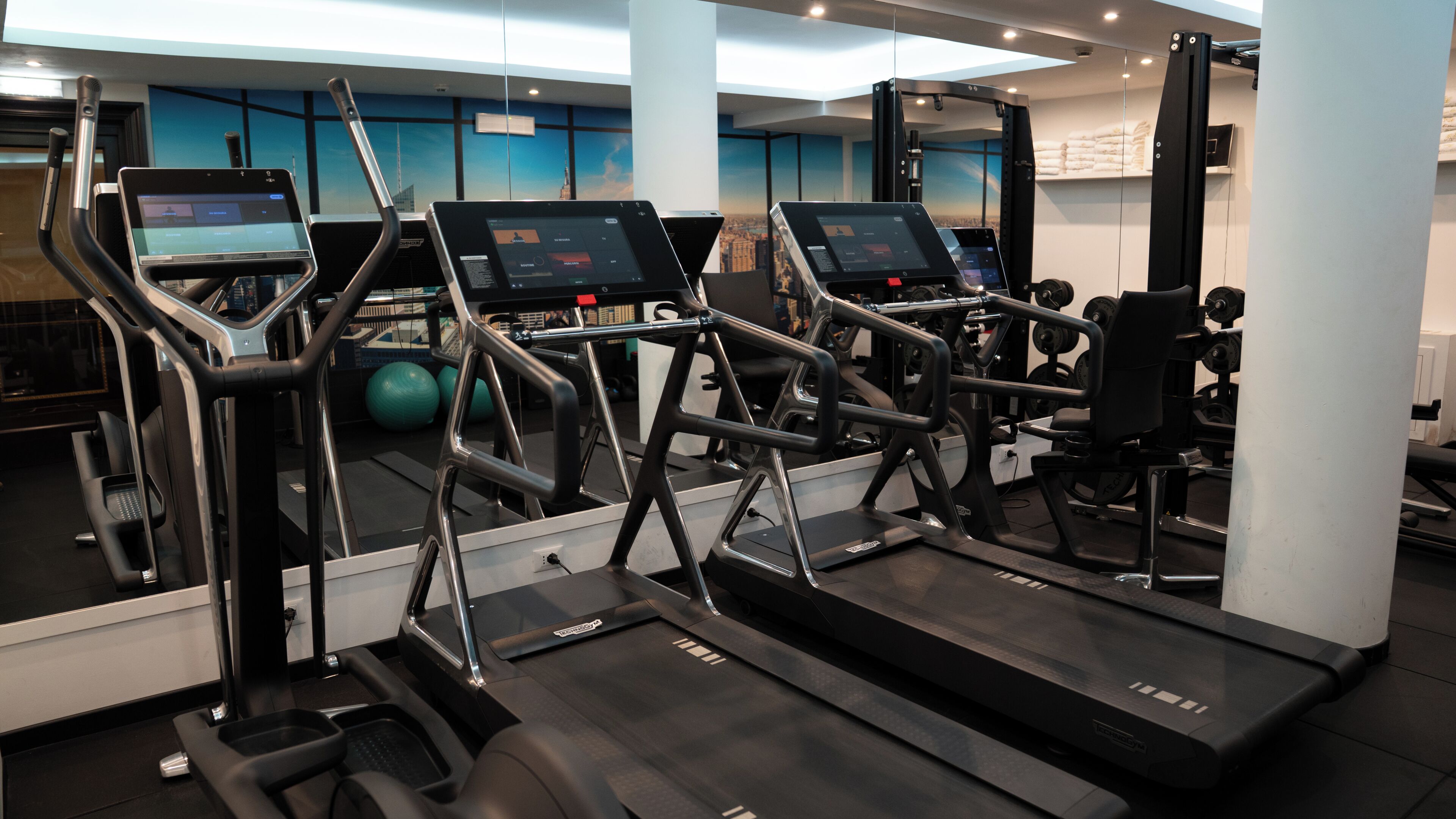 Un gimnasio con cintas de correr, bicicletas estáticas y máquinas de pesas.