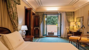 A hotel room with a bed, a desk, a chair, a lamp, and a view of the outdoors. - River Château Hotel (Rome)