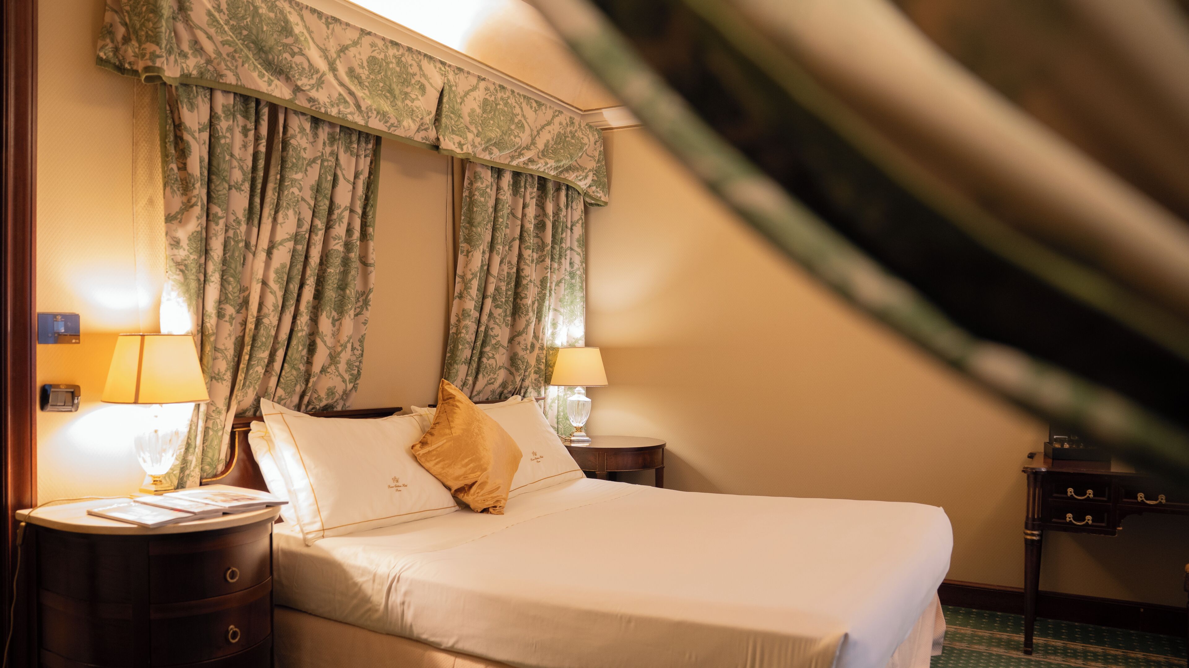 Une chambre d’hôtel avec un lit, deux lampes de chevet, une table de chevet et une fenêtre avec des rideaux.